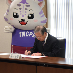 協定書にサインをする樋口理事長の写真
