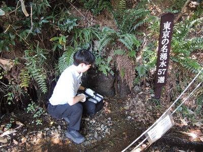 打ち水イベントに備えて、職員が西府町湧水から水を採取している様子の写真