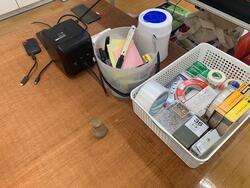 机の上の雑雑とした道具類と小さな陶器