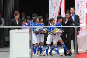 画像　花束を運ぶ市内の少女サッカーチーム「府中なでしこ」の選手